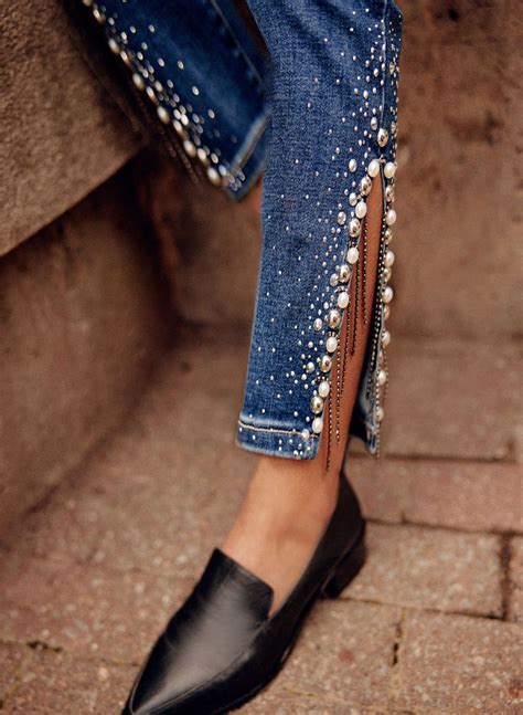 A Woman S Legs In Jeans And Black Shoes With Pearls On The Bottom Of Them