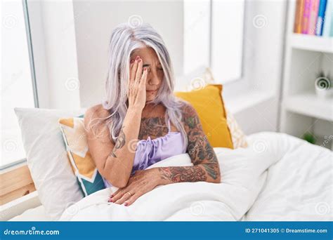 Middle Age Grey Haired Woman Stressed Sitting On Bed At Bedroom Stock