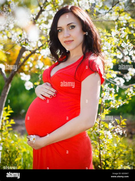 Portrait Of Beautiful Pregnant Woman In Red Dress In The Flowering