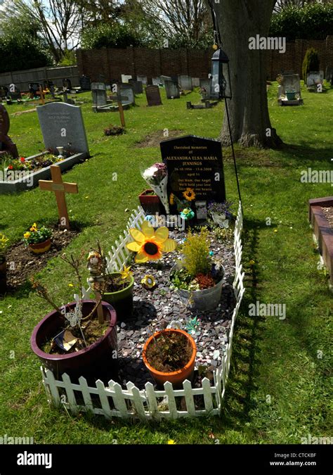 Grave With White Picket Fence Flowers Pot Plants And Windmills