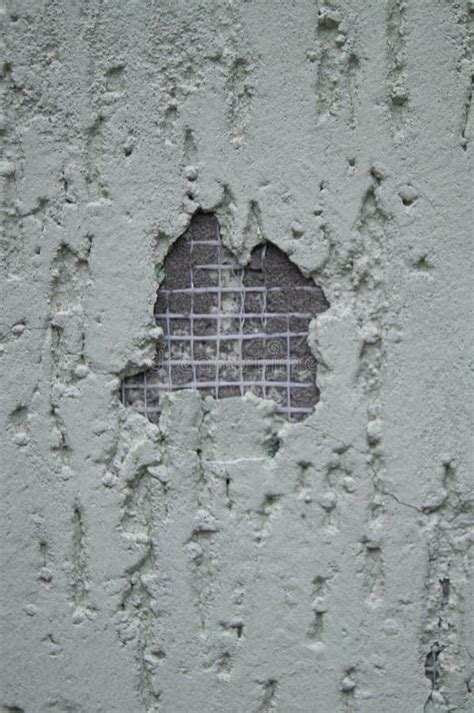 Damaged Plaster Exterior Wall With Exposed Wire Mesh And Textured