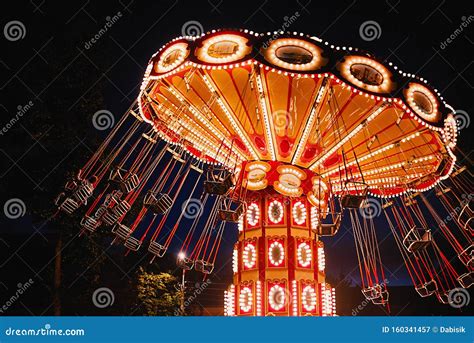 Illuminated Swing Chain Carousel In Amusement Park At The Night Stock