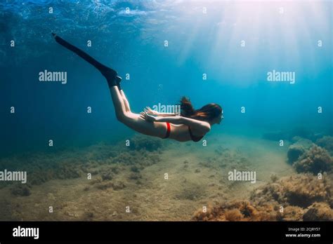 Freediver Slim Woman In Bikini Glides In Blue Sea And Sun Rays