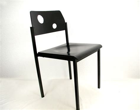 A Black Chair Sitting On Top Of A White Floor Next To A Wall With Holes