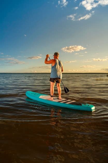 Premium Photo A Man In Shorts Stands With A Paddle On A Sup Board At