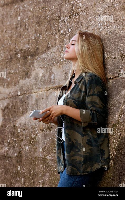 Beautiful Girl Leaning Against A Concrete Wall In A Suburban Area She