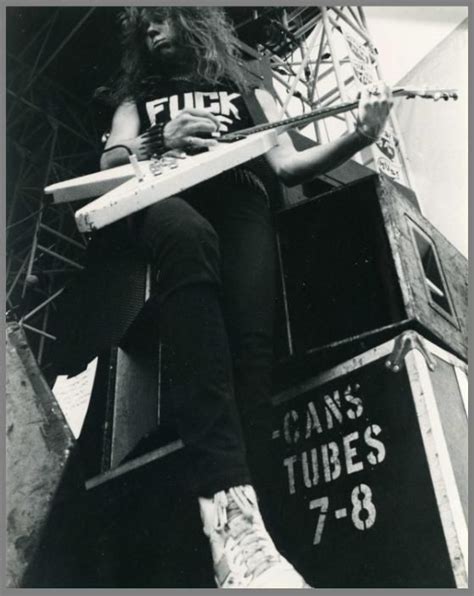 A Man With Long Hair Sitting On Top Of A Sign