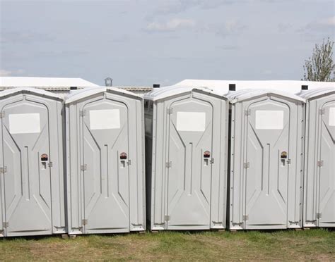 a row of portable toilets sitting in the grass