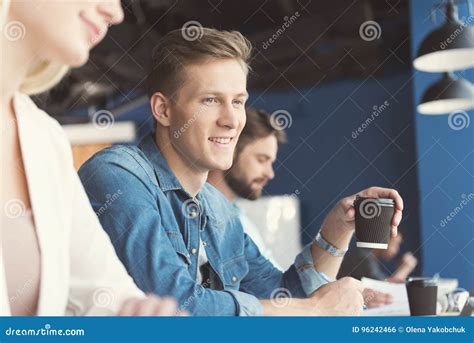 Cheerful Youthful Guy And Other Employees Doing Job In Office Stock