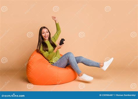 Portrait Of Lovely Cheerful Girl Sitting On Bag Chair Playing Video Game Having Fun Isolated