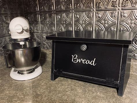 A Kitchen Counter With A Mixer And Bread Box