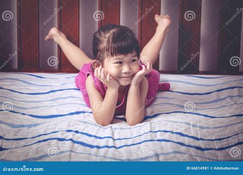 Portrait De Fille Mignonne Se Trouvant Nu Pieds Sur Le Lit Dans La