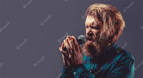 Premium Photo Man With A Beard Holding A Microphone And Singing