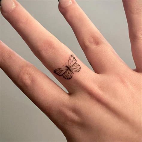 A Woman S Hand With A Small Butterfly Tattoo On Her Left Thumb And Finger