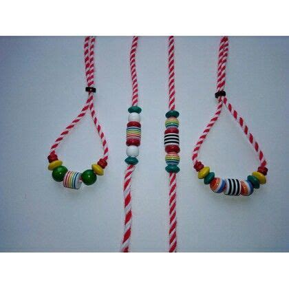 Three Colorful Necklaces Hanging From Strings On A White Wall With Red