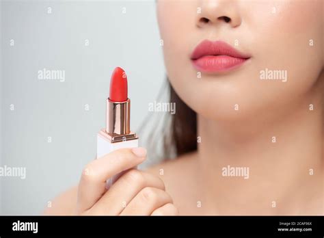 Beautiful Young Woman Applying Red Lipstick On Color Background