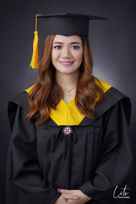 A Woman Wearing A Graduation Cap And Gown Posing For A Photo In Front