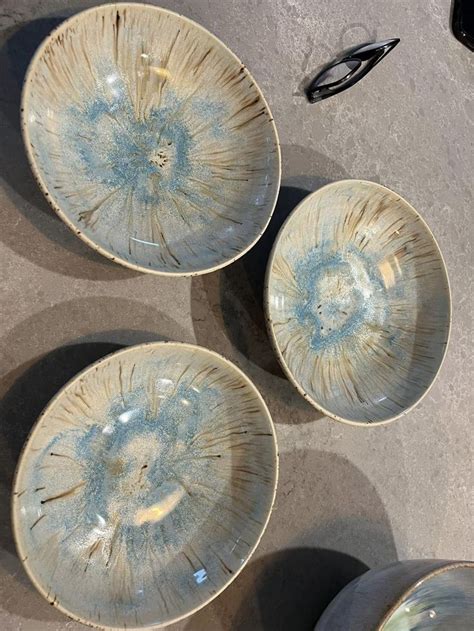 Three Bowls Sitting On Top Of A Cement Floor Next To A Pair Of Black