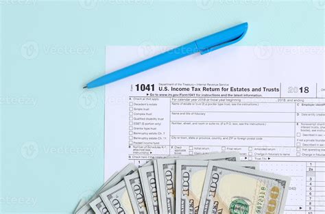 1041 Tax Form Lies Near Hundred Dollar Bills And Blue Pen On A Light