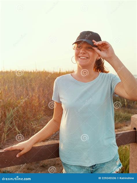 Smiling Teenage Girl In Baseball Cap Standing Near The Field Stock