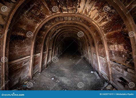 The Tunnel Of An Old Abandoned Mine With Rusty Remnants Of Trolleys