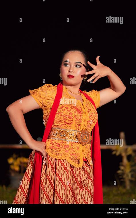 Balinese dancers in yellow color traditional costumes present the dance in front of visitors in ...