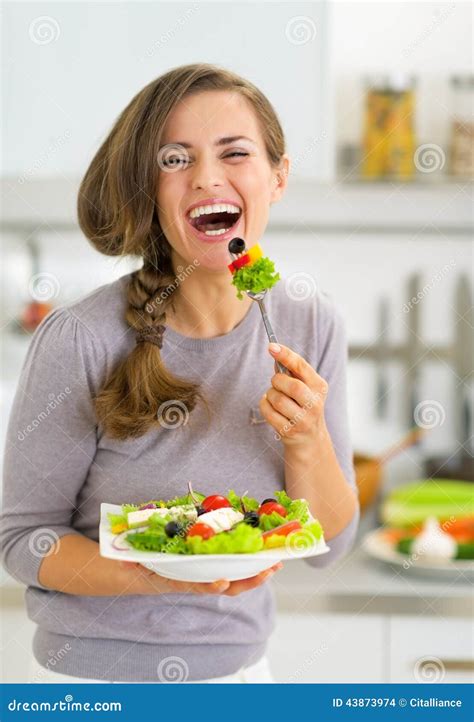 Jovem Mulher Que Come A Salada Grega Na Cozinha Foto De Stock Imagem