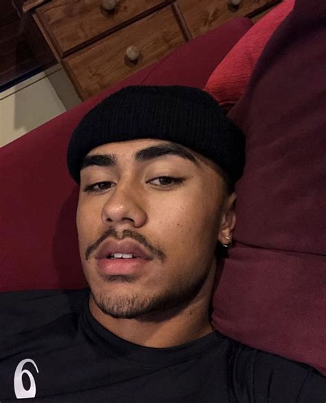 A Man Laying On Top Of A Red Couch Wearing A Black Shirt And Beanie