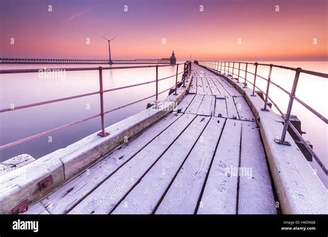 Blyth pier on the Northumberland coast at Blyth Harbour, an old wooden curving pier on a cold ...