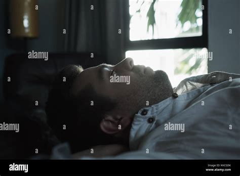 Portrait Of A Young Caucasian Man From Above Sleeping In A Dark Bed