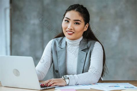 美丽的亚洲女商人使用笔记本电脑和微笑在办 包图企业站