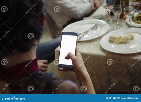 Woman Sits At The Table And Looks Into The Phone Screen Stock Image