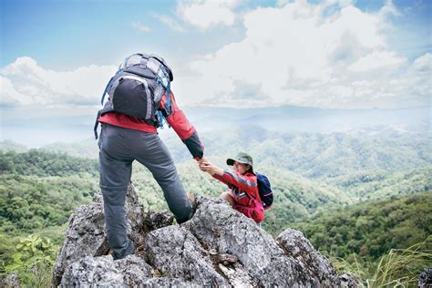 Person Hike Friends Helping Each Other Up A Mountain Man And Woman