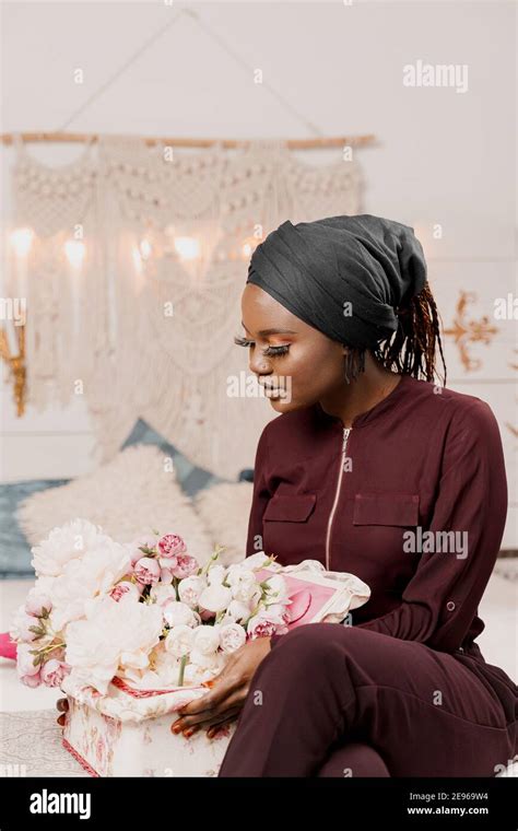 Muslim girl with flowers seats and looks at bouquet. African young ...