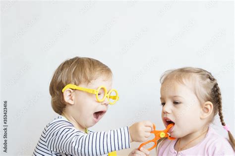 Two Children Play Doctor In The Nursery Brother In Yellow Glasses