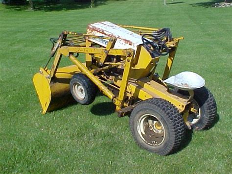 A Yellow Tractor Sitting On Top Of A Lush Green Field Next To A White