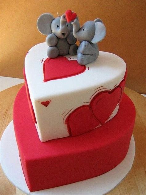 Two Elephants Sitting On Top Of A Red And White Heart Shaped Cake With