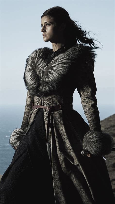 a woman dressed in medieval clothing standing on top of a hill