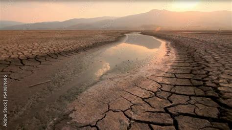 Landscape Of River Drying With Dry Cracked Earth At Sunset Metaphor