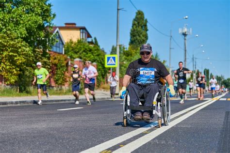 Disabled Man In Wheelchair Riding Between Runners Editorial Photography