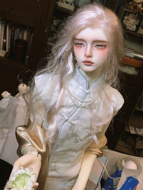 A Doll With Long White Hair Is Sitting On A Table