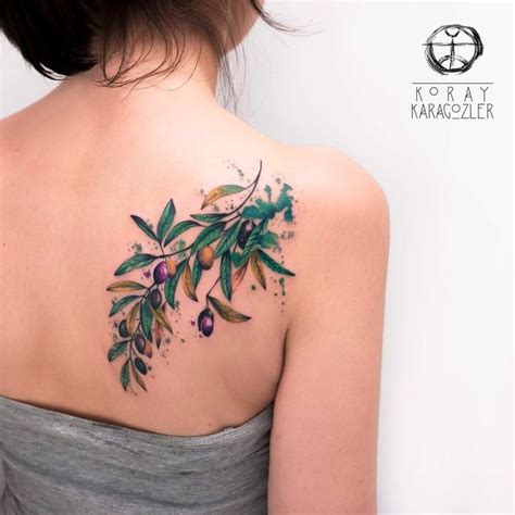 The Back Of A Woman S Shoulder With An Olive Branch Tattoo