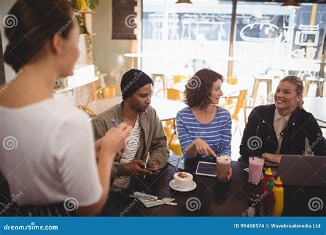 Smiling Woman Siting With Friends Ordering Food To Waitress Stock Photo