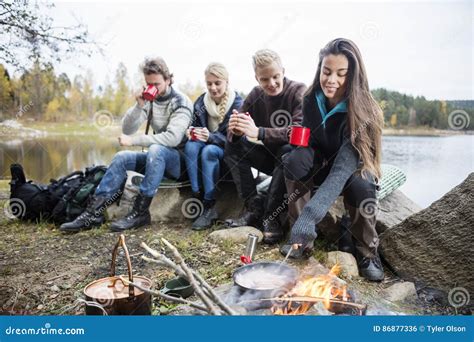 Mulher Que Cozinha O Alimento Na Fogueira Os Amigos No Fundo Foto