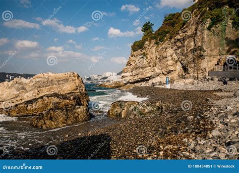 Beautiful Rocky Beach With A Cliff And A Blue Sky In The Background