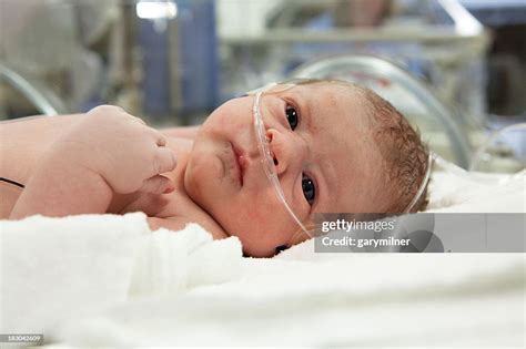 Newborn Baby With Iv Wires And Hospital In The Background High Res