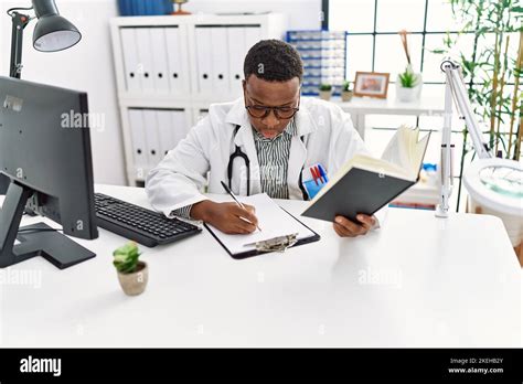 Young African Man Working As Doctor Writing Notes At Medical Clinic