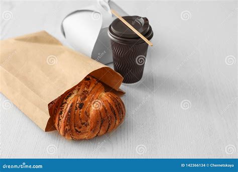 Paper Bag With Pastry And Takeaway Food On Wooden Table Stock Photo