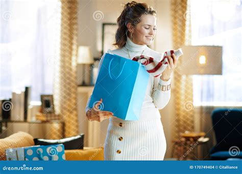 Smiling Woman With Blue Shopping Bag Checking Purchased Sweater Stock