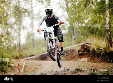 Downhill Mountain Bike Rider Jump Over Springboard In Forest Trail Race